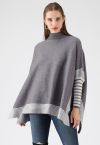 Sdraiato in un maglione a mantella lavorato a maglia oversize a righe grigie