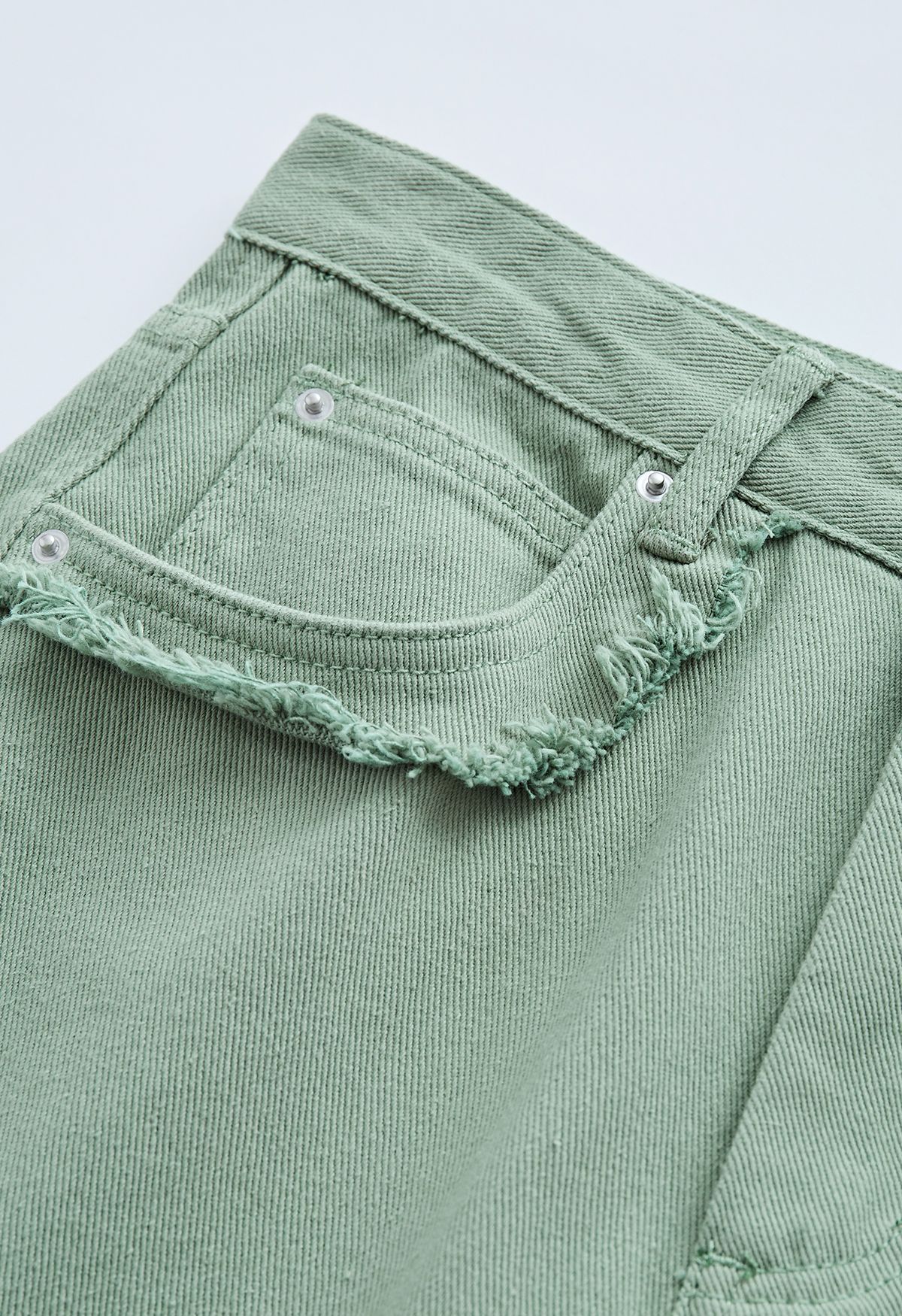 Jeans svasati classici con tasche e dettagli sfrangiati color salvia
