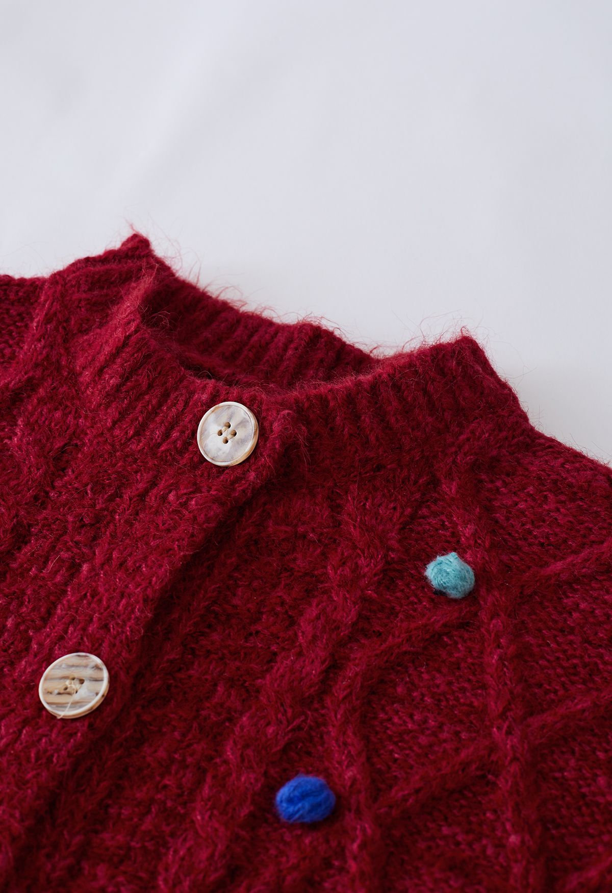 Cardigan in maglia a rombi con pompon colorato in rosso