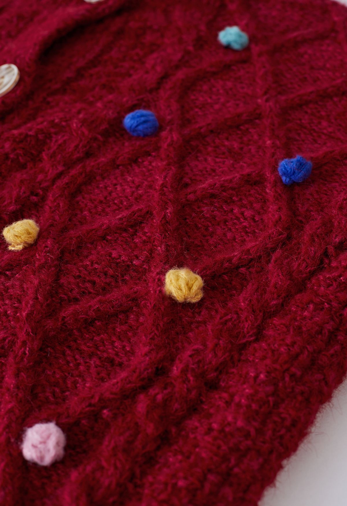 Cardigan in maglia a rombi con pompon colorato in rosso