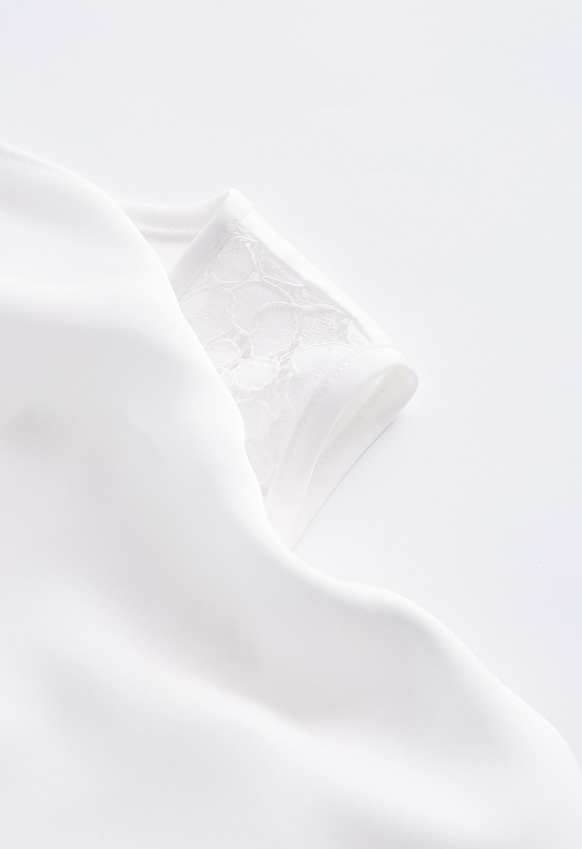 Top asimmetrico in raso con drappeggio a spalla fredda in bianco