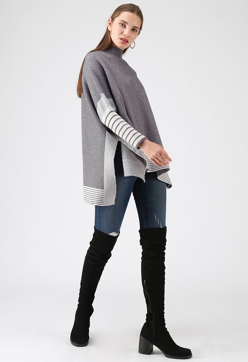 Sdraiato in un maglione a mantella lavorato a maglia oversize a righe grigie
