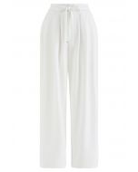 Pantaloni bianchi a gamba larga con coulisse in vita e dettagli plissettati